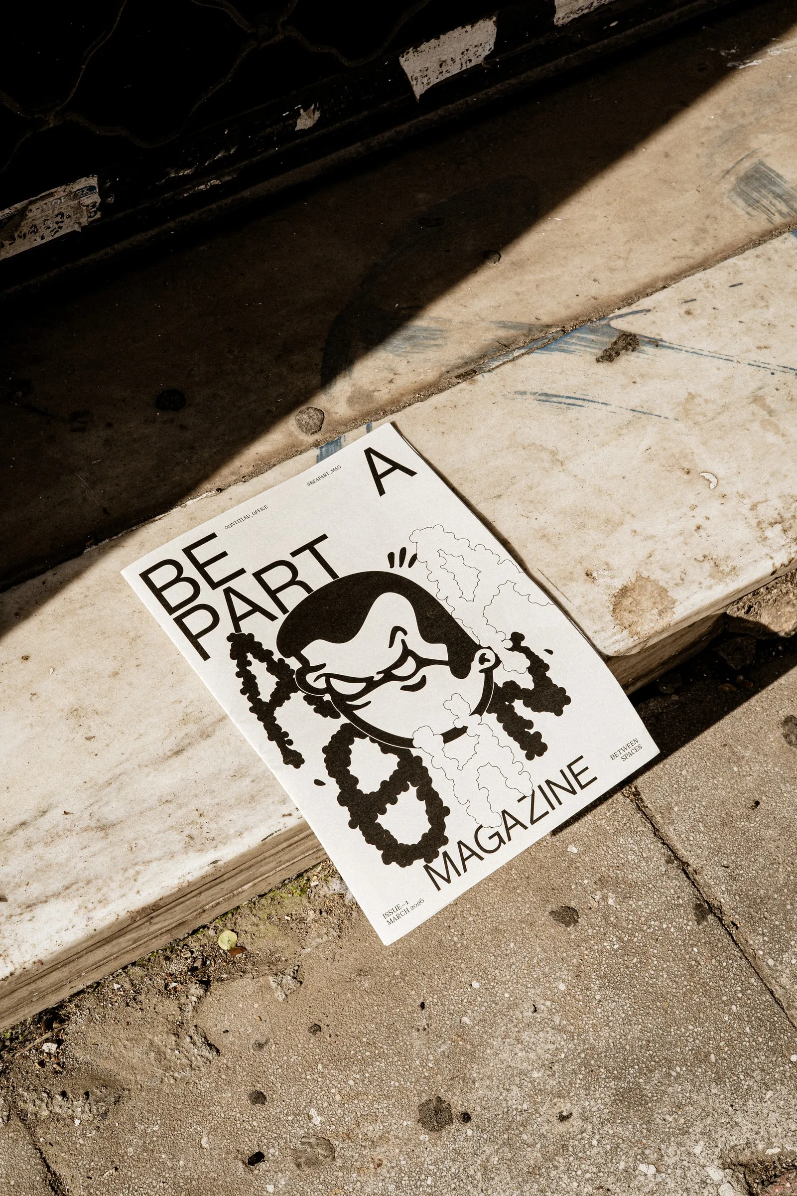 The Be A Part magazine lying on a sunlit pavement kerb