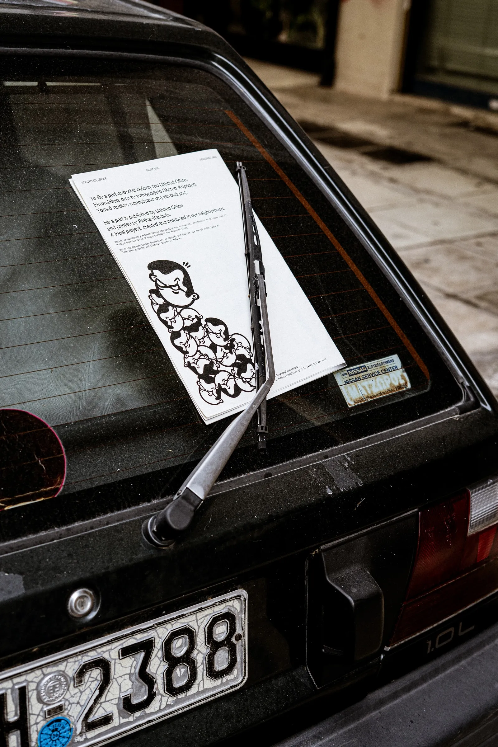 The magazine tucked under the rear wiper of a parked car