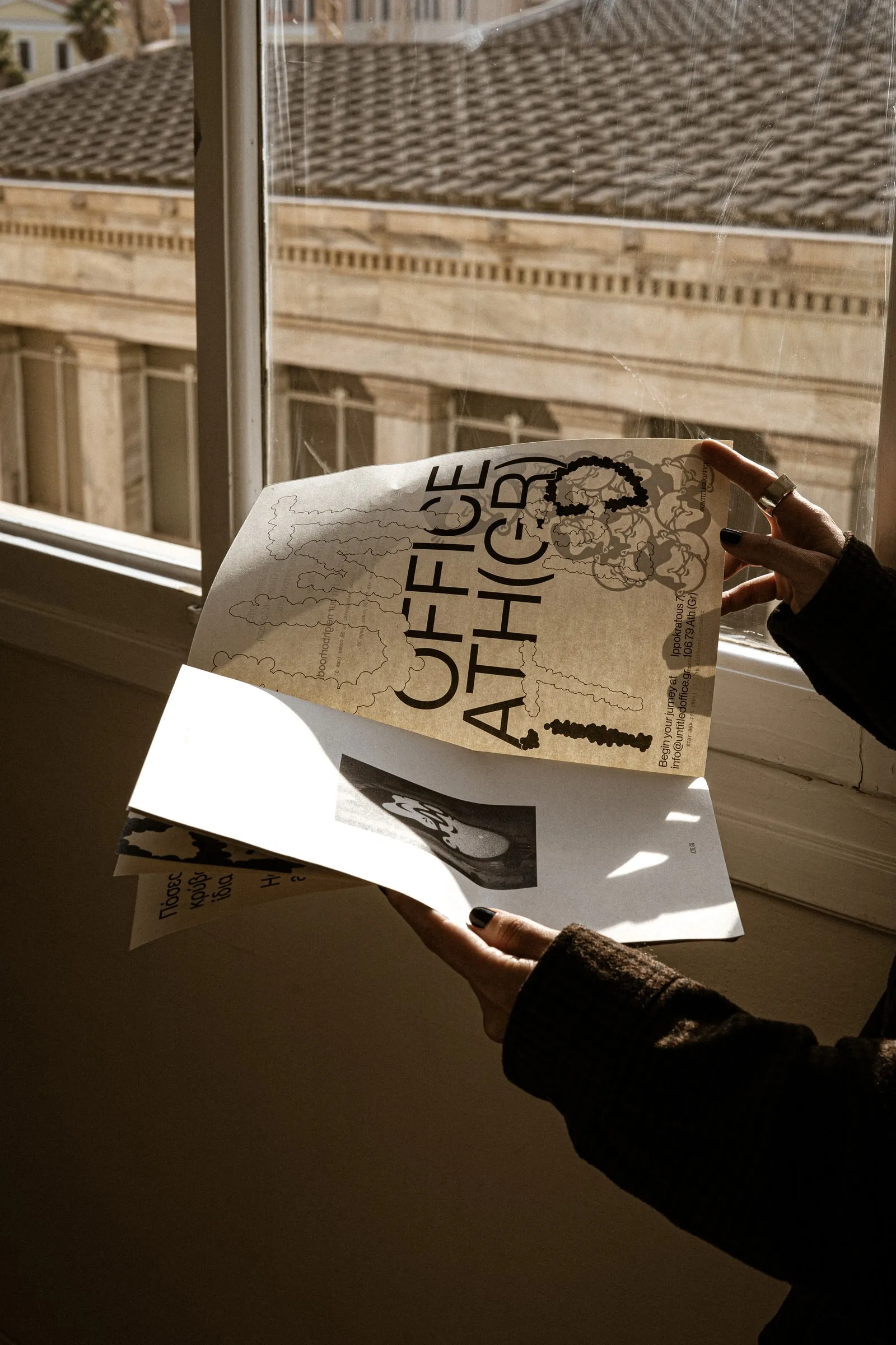 Hands holding the magazine open by a sunlit window
