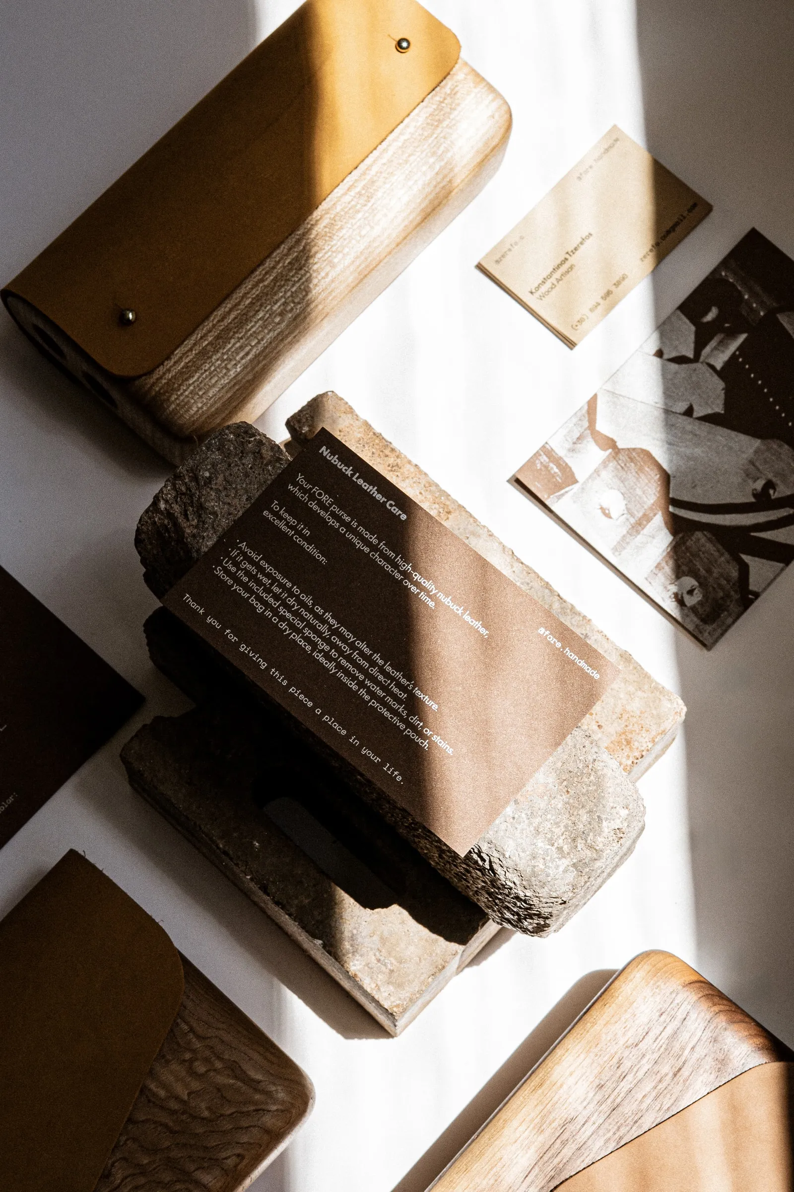 Wooden bags, cards and a stone holding a printed text card, lit by a strip of sun