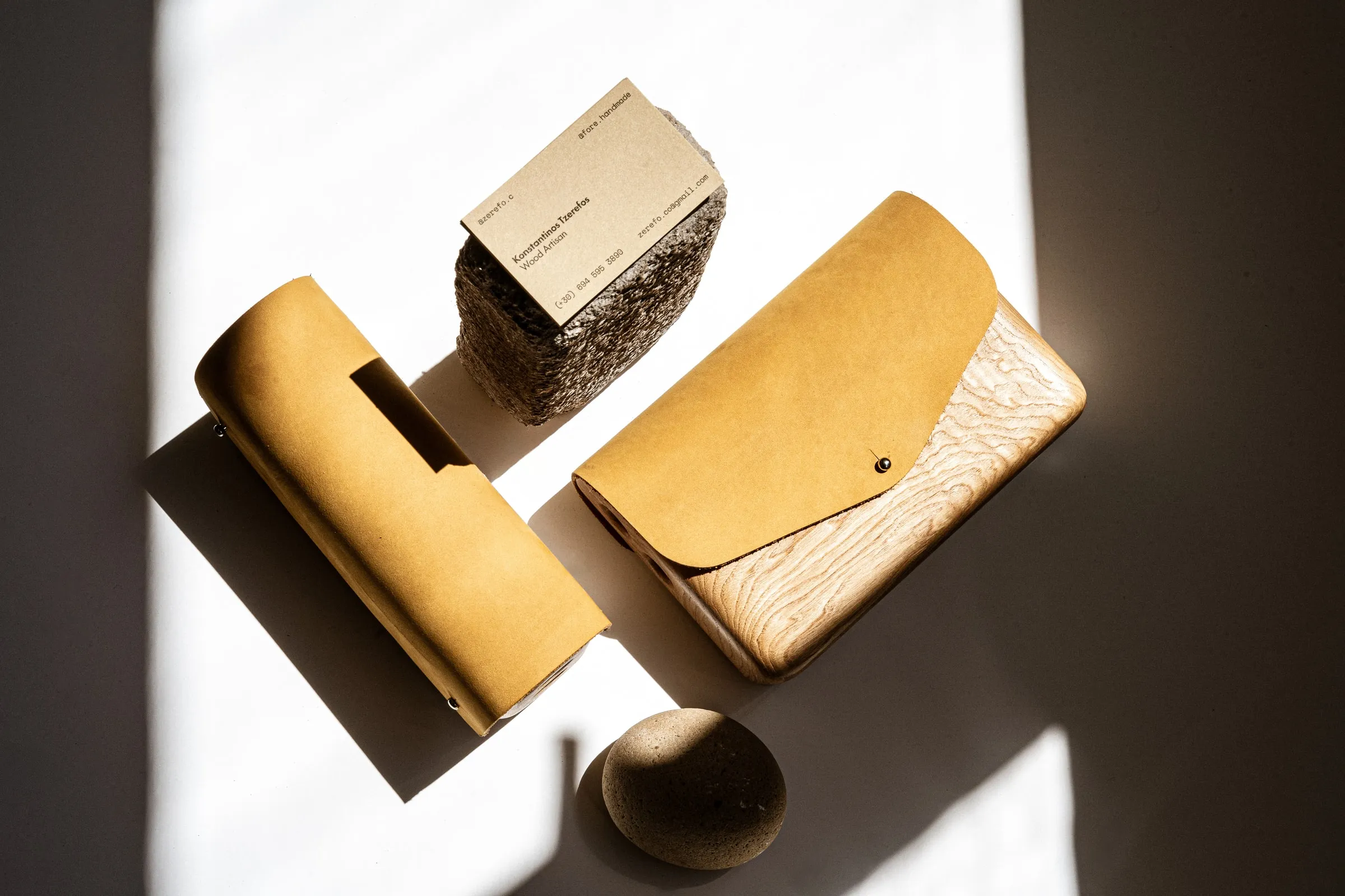 Two wood-and-suede bags with a small card on a stone and a round pebble