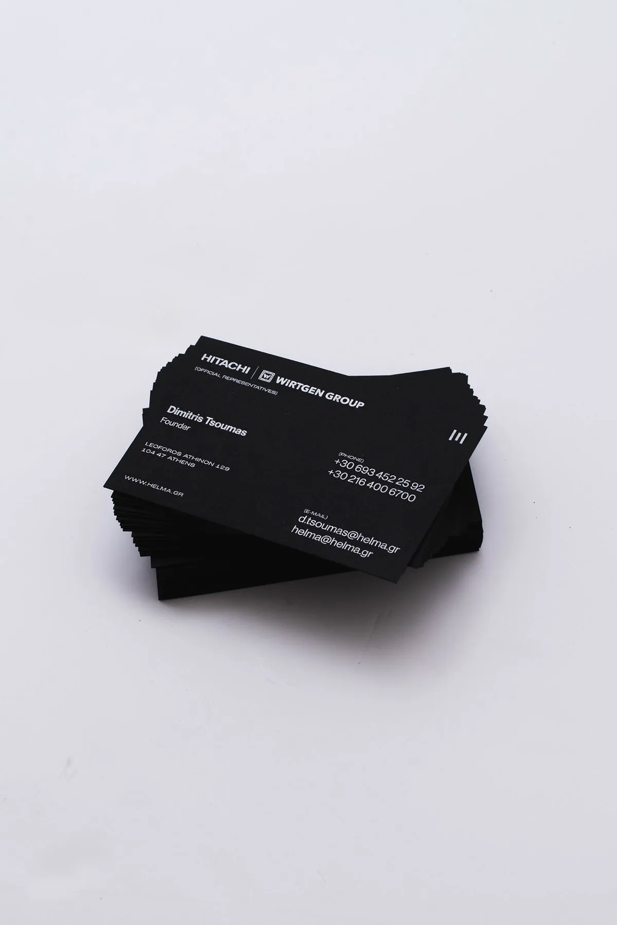 A small stack of black Helma business cards on a white surface