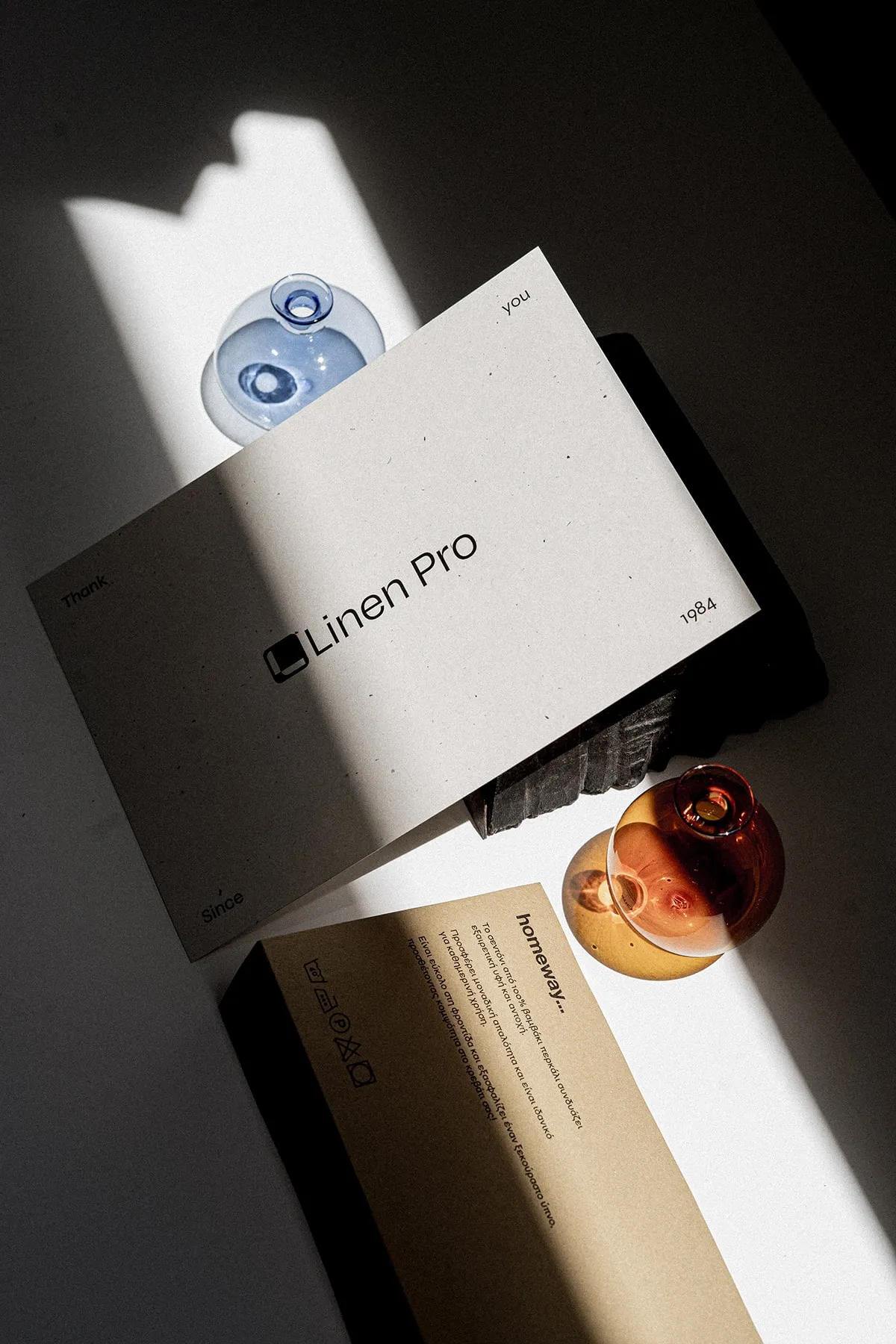 A Linen Pro card resting on a dark folder and a kraft sheet, an amber glass globe below