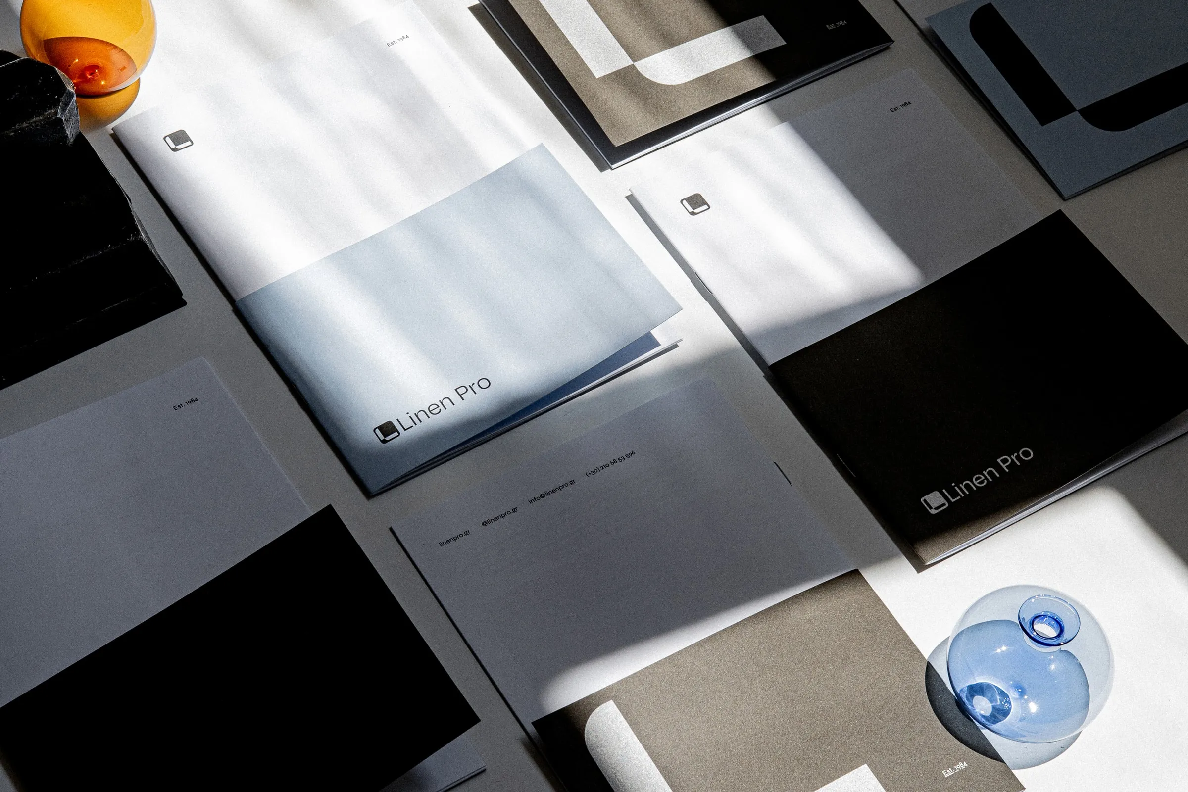 Flat lay of Linen Pro folders, a pale blue cover and a black folder with glass globes