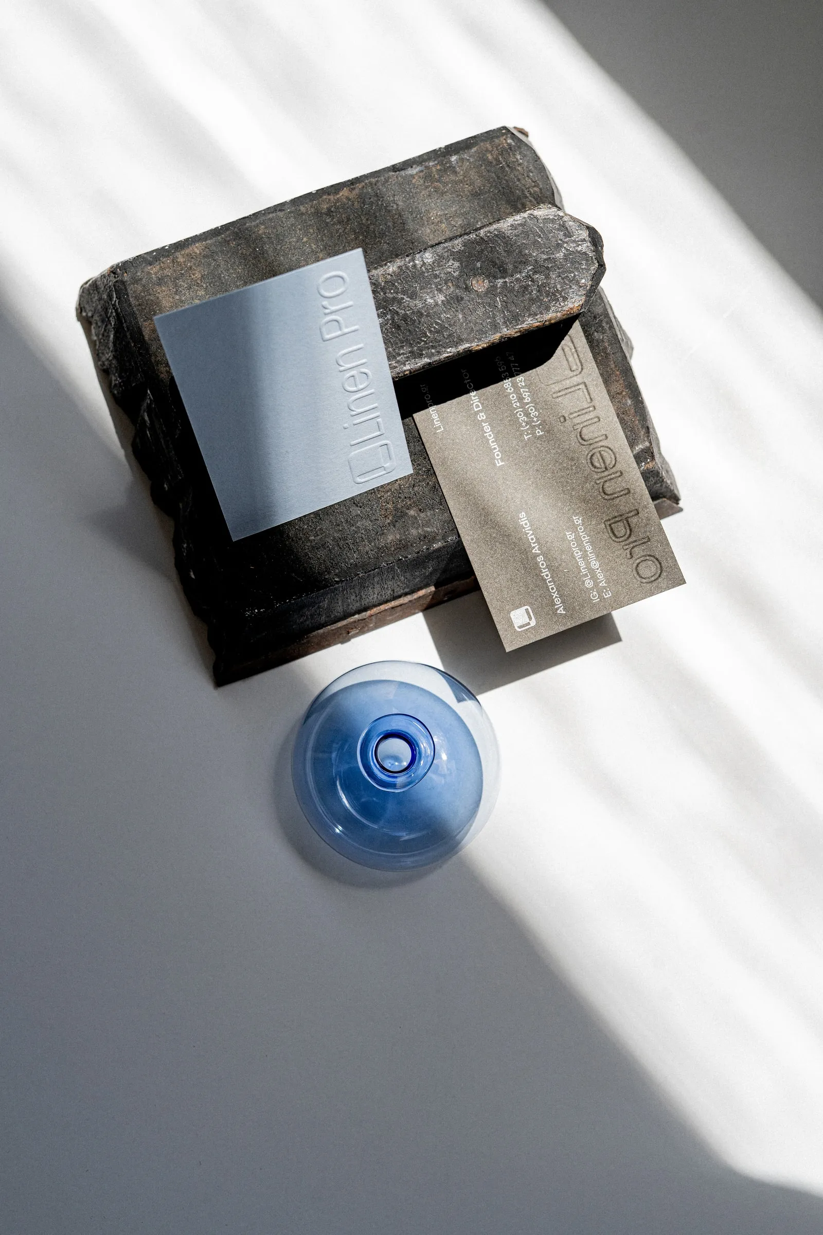 Pale blue and kraft cards propped on a dark brick, a blue glass globe in front