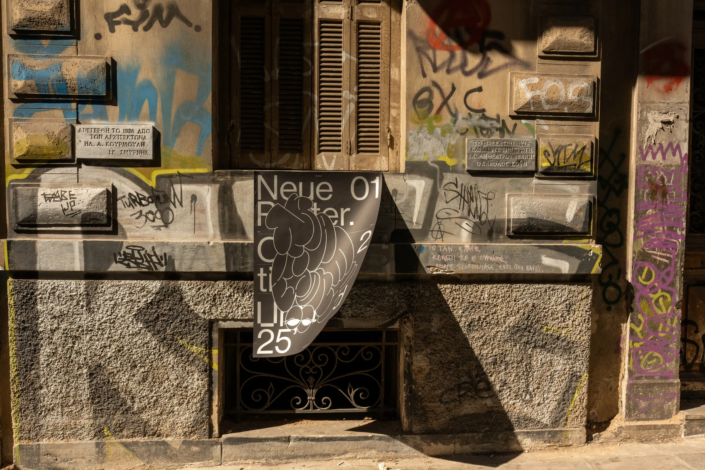 The poster hanging from a ledge on a graffiti-covered building front