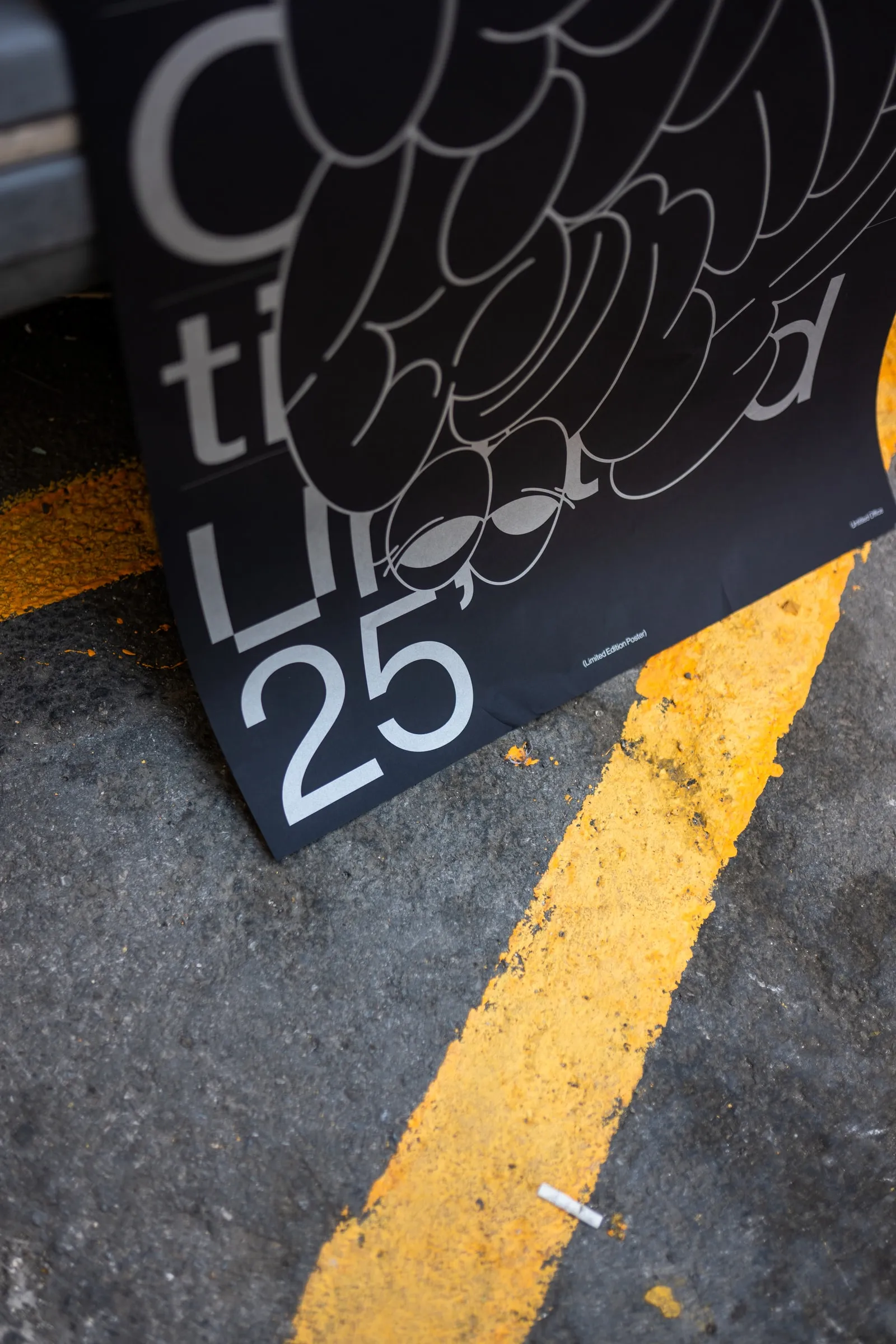 The poster lying on asphalt beside a yellow road marking