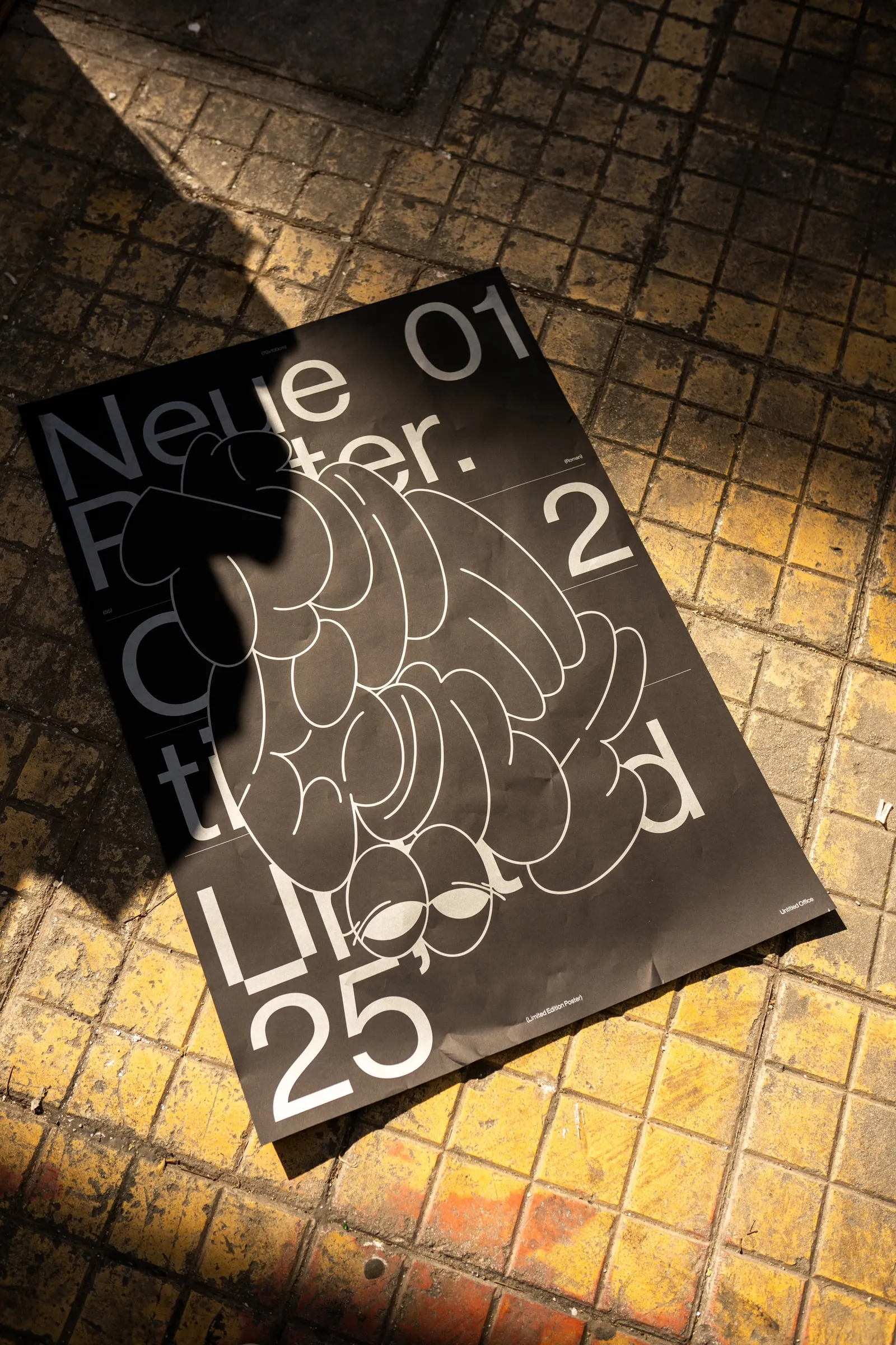 The poster lying on a sunlit tiled pavement