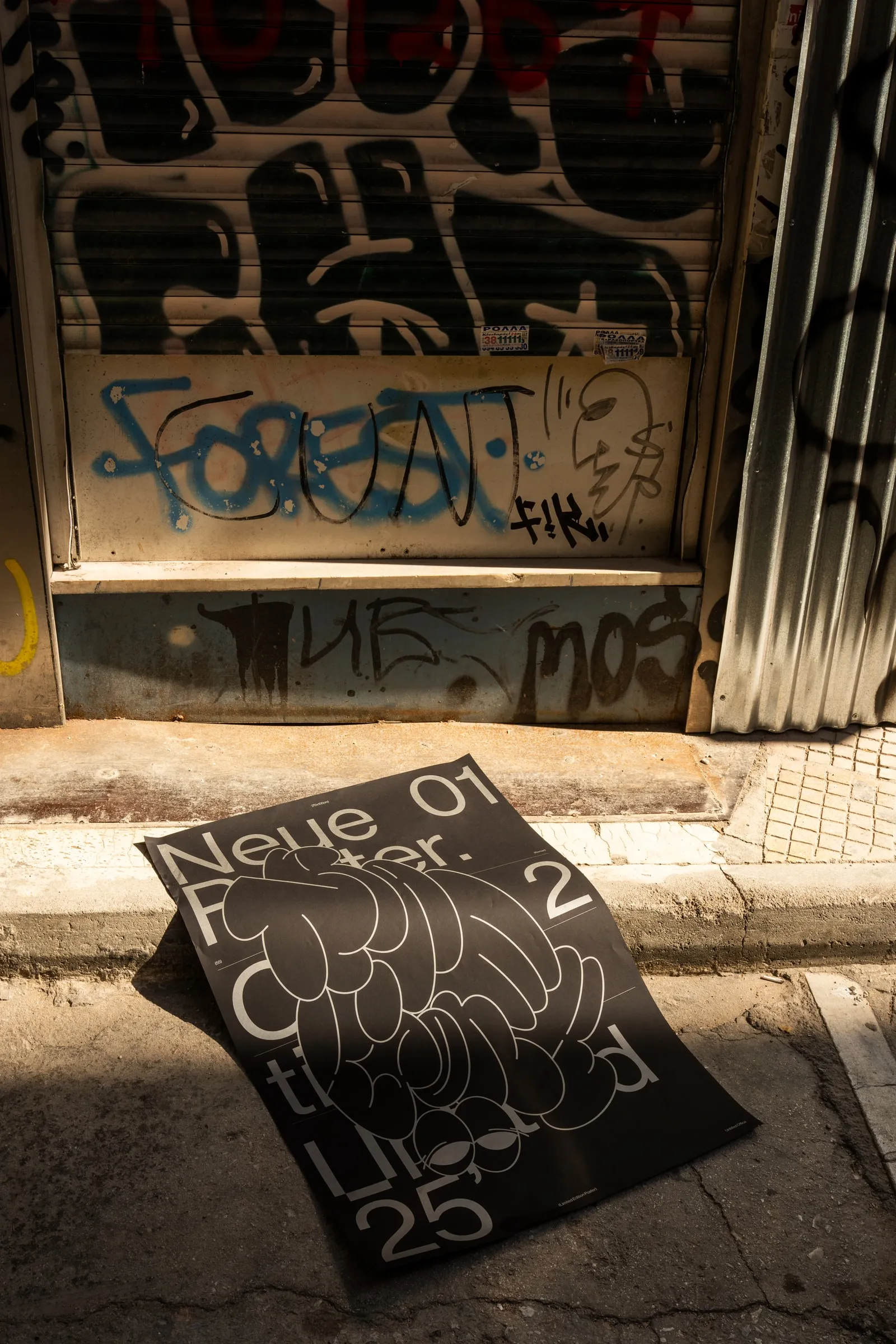 The poster dropped on the pavement in front of a tagged shutter