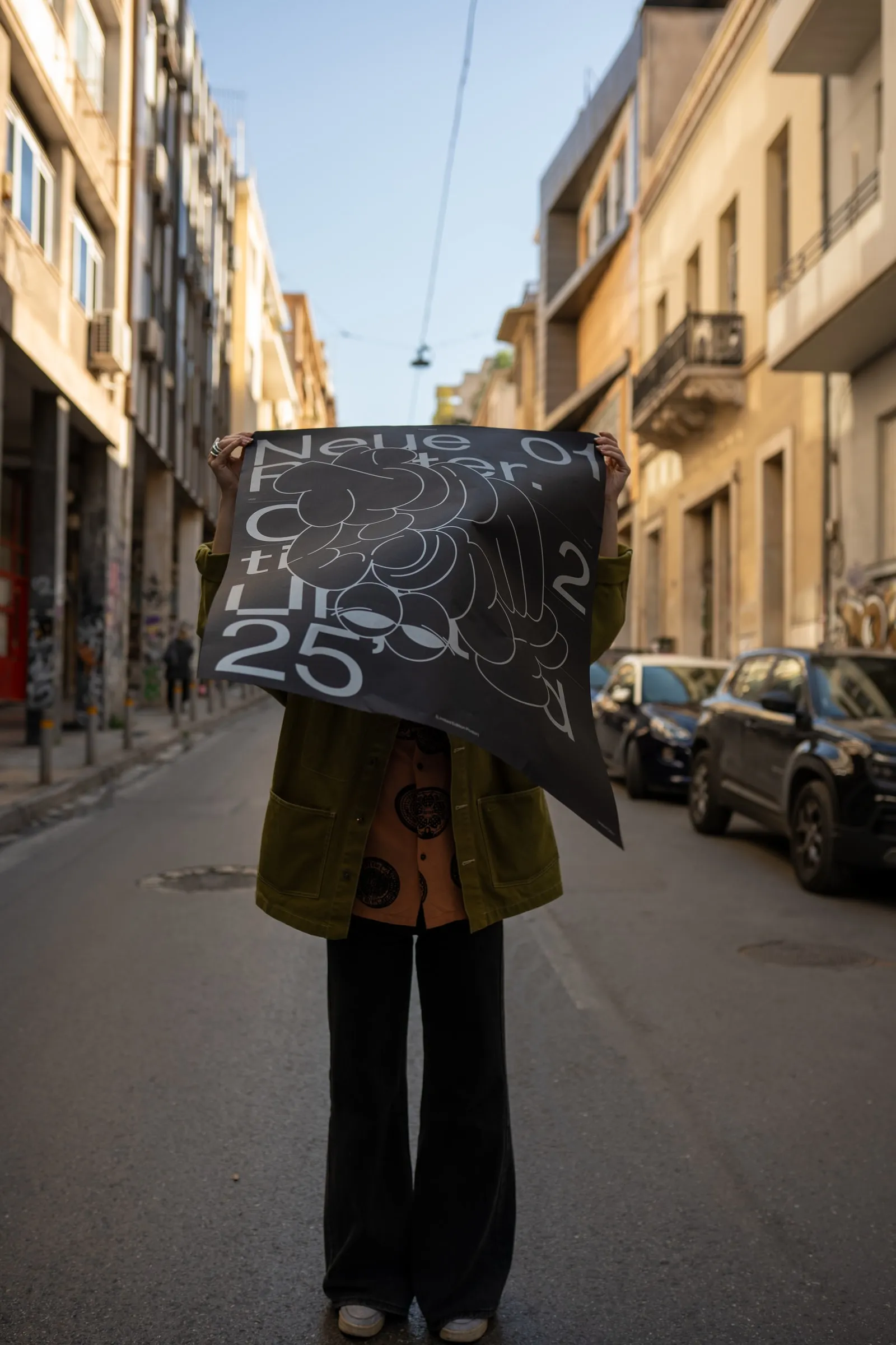 Someone holding the poster in front of their face in the middle of a street