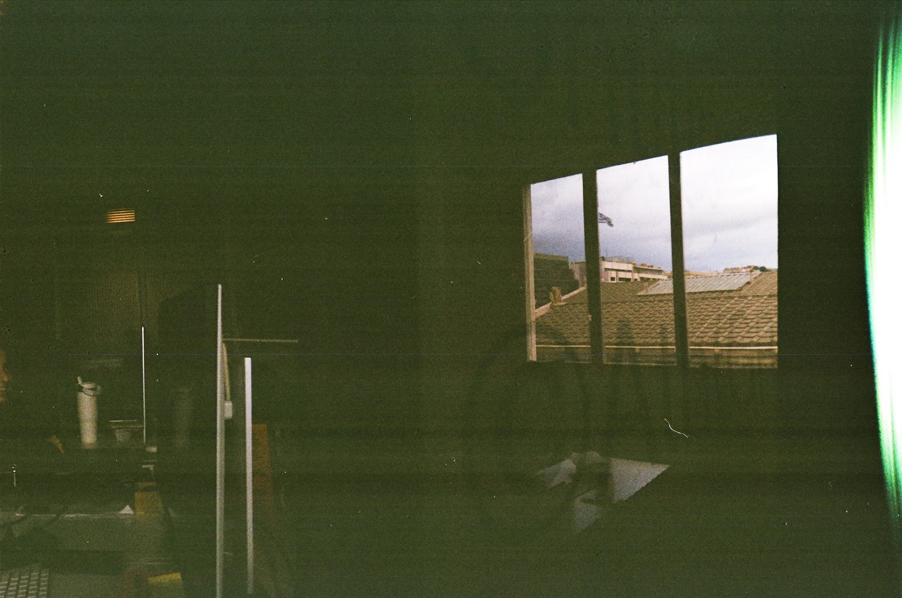 Dark studio interior on film, with a bright window and a green light leak along one edge