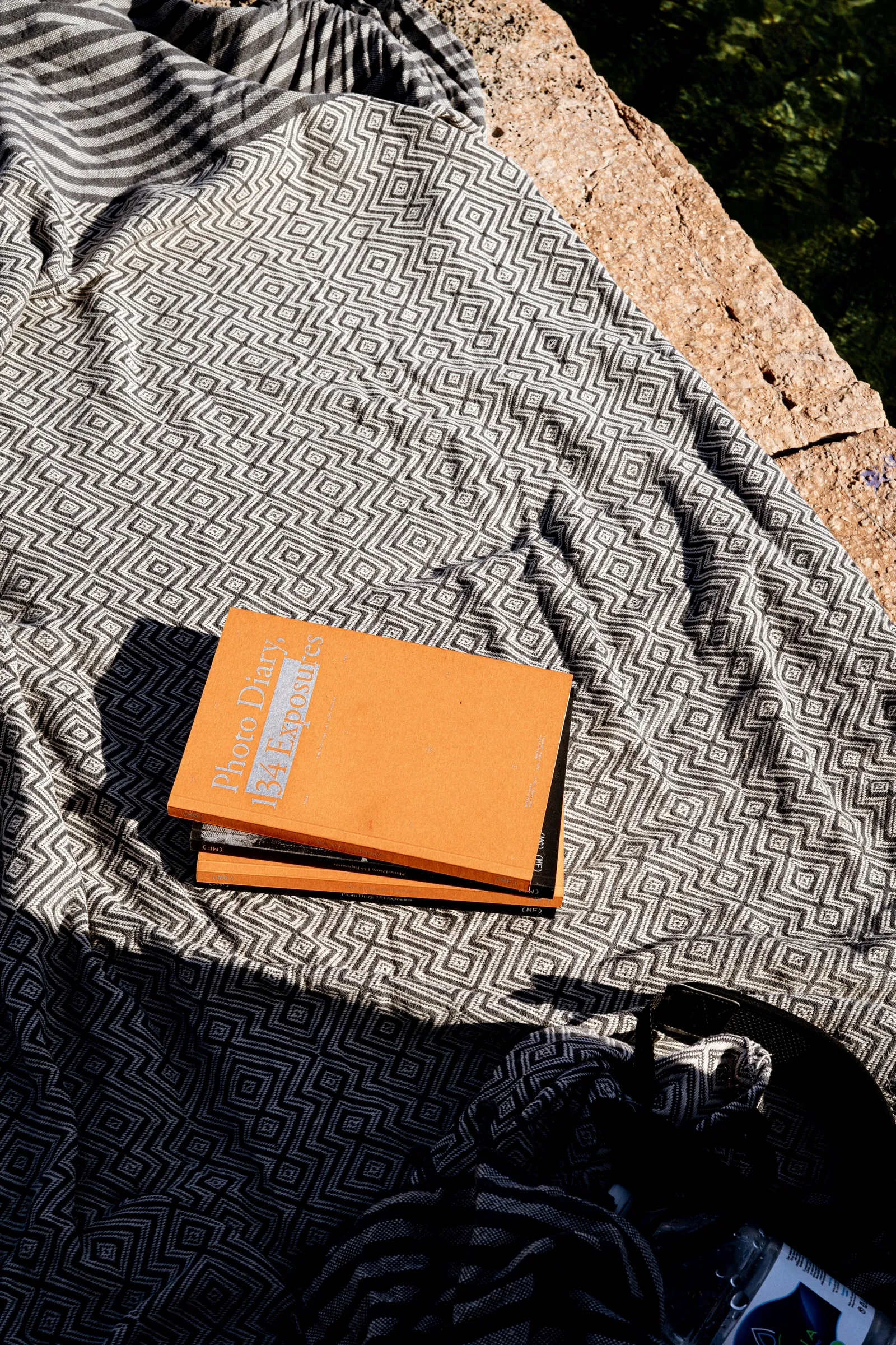 The orange-covered edition lying on a black and white patterned blanket