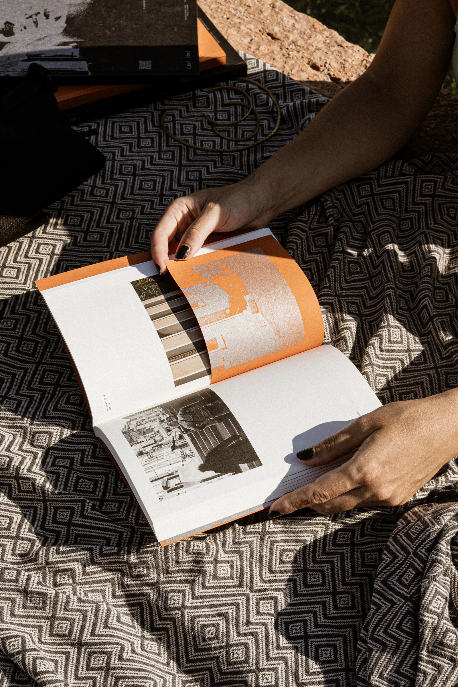 Hands turning a page of the photobook on a patterned blanket