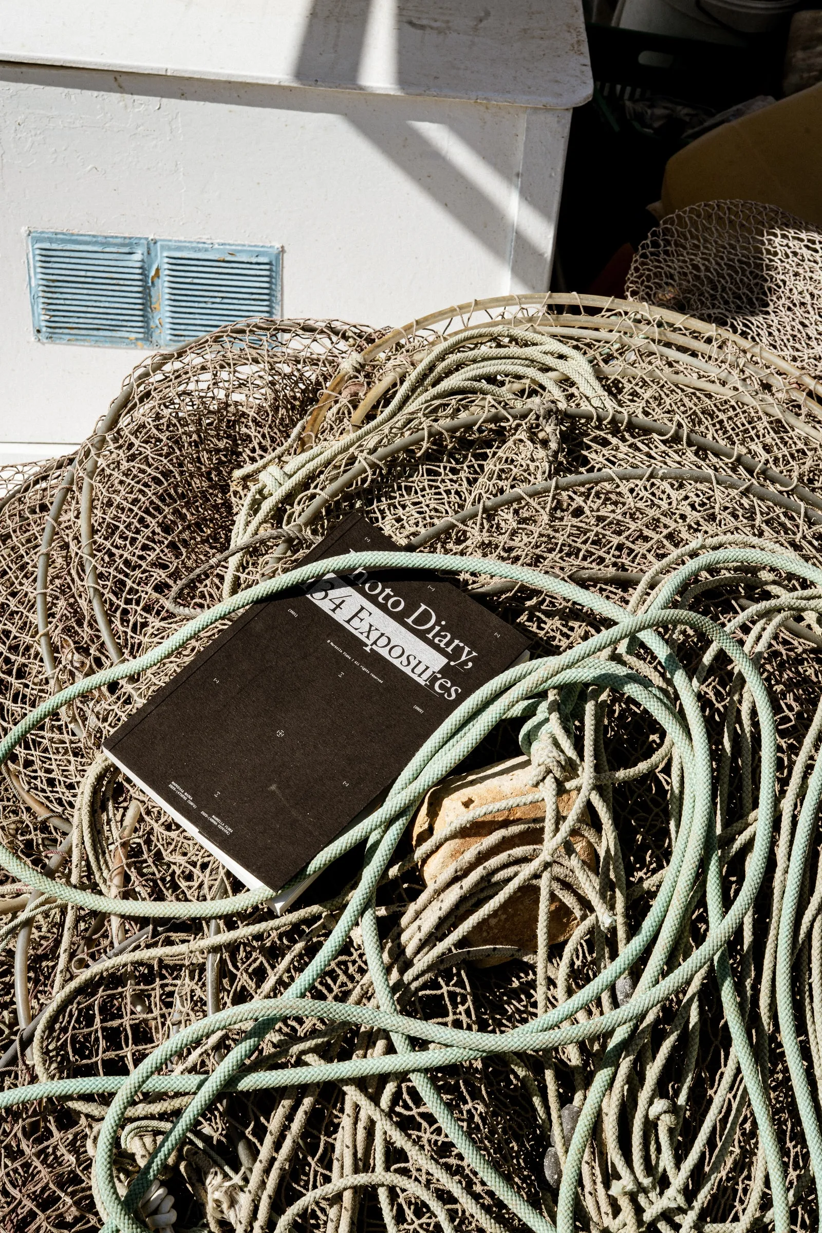 The black photobook lying on a heap of fishing nets and ropes