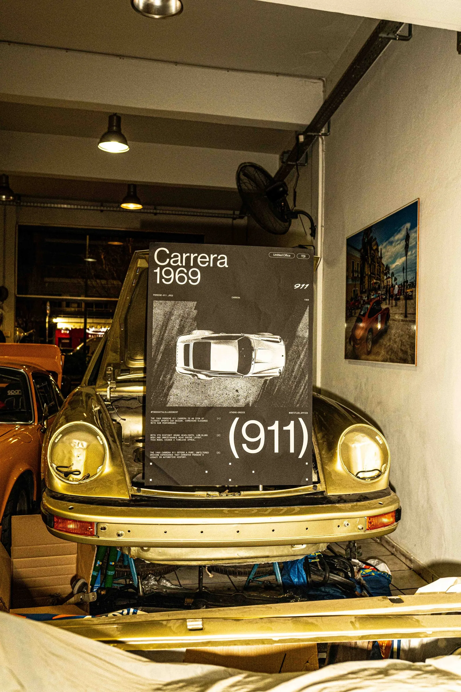 The poster on the bonnet of a gold Porsche 911 inside a workshop