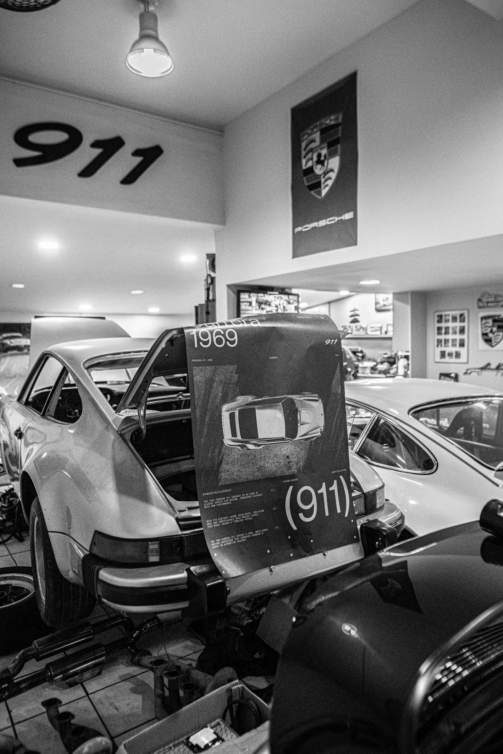 Black-and-white photo of the poster on a white 911 in a Porsche workshop