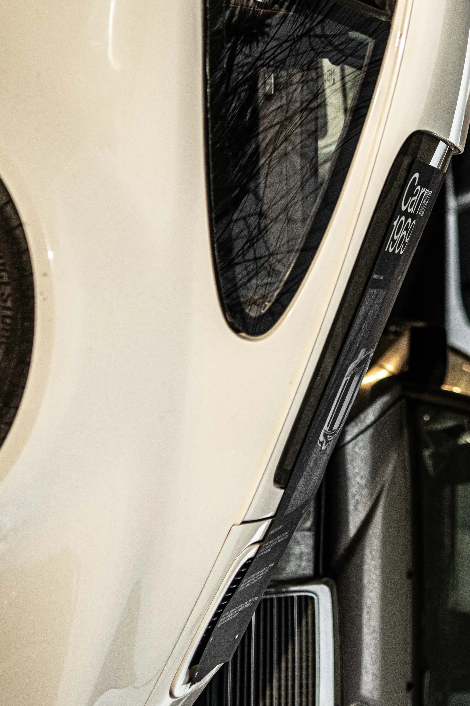 Close-up of the white 911's side window with the edge of the poster