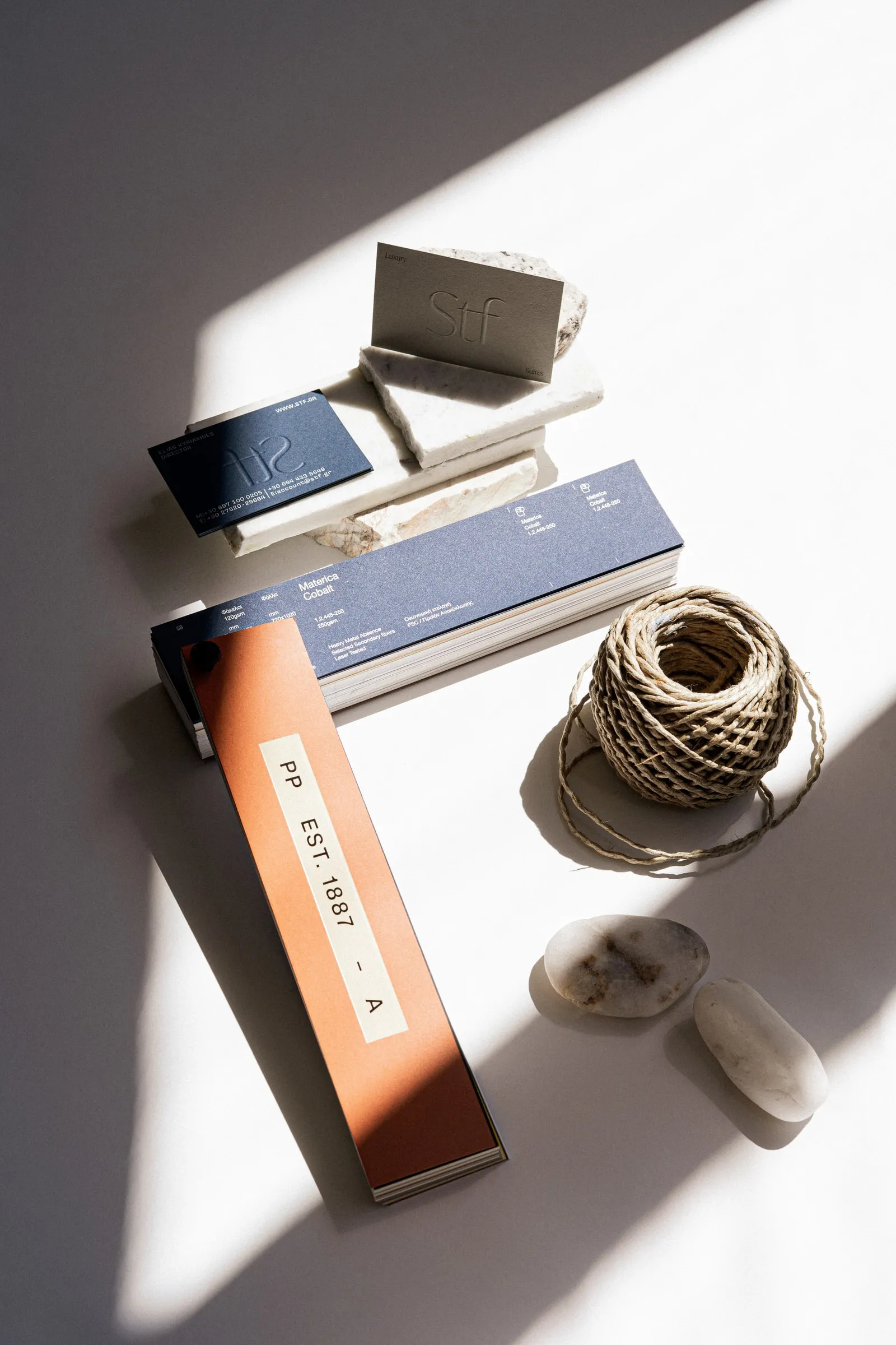 Flat lay of STF cards on marble with a Materica paper swatch book, a ball of twine and white pebbles