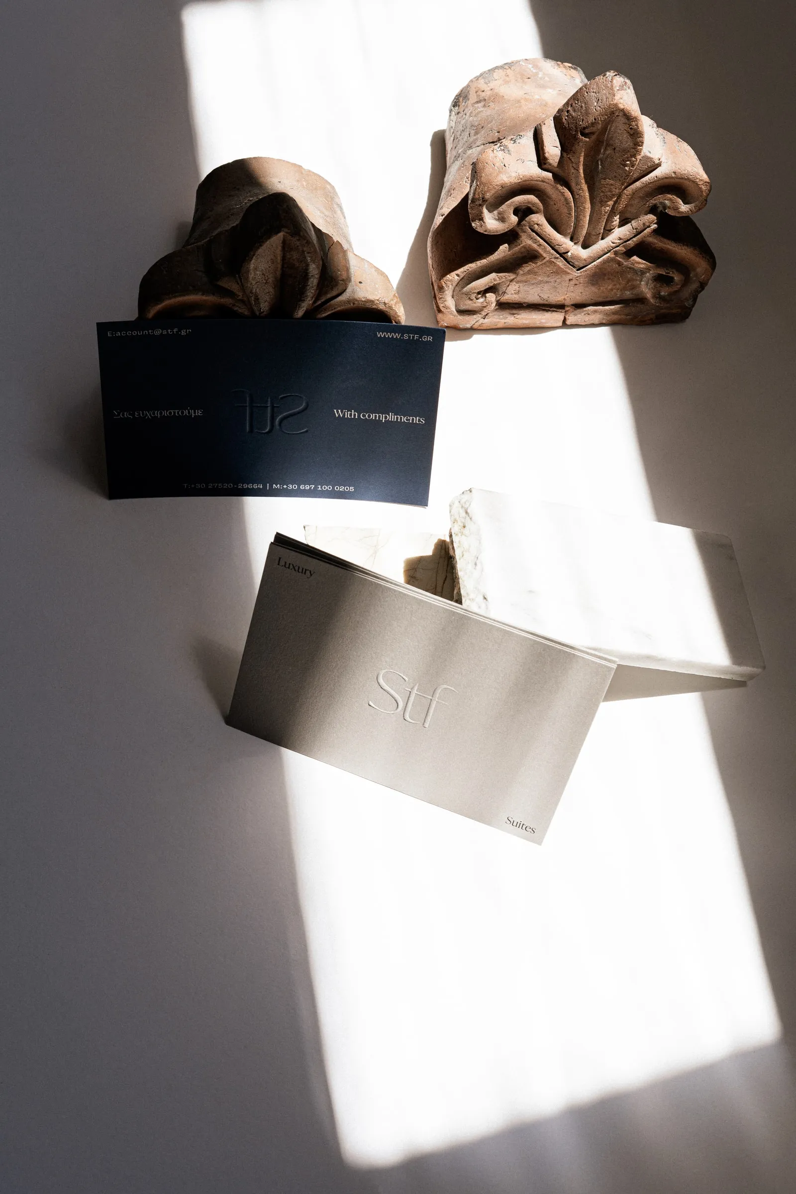 A navy compliments card and a clay-coloured STF card beside terracotta ornaments and a marble block