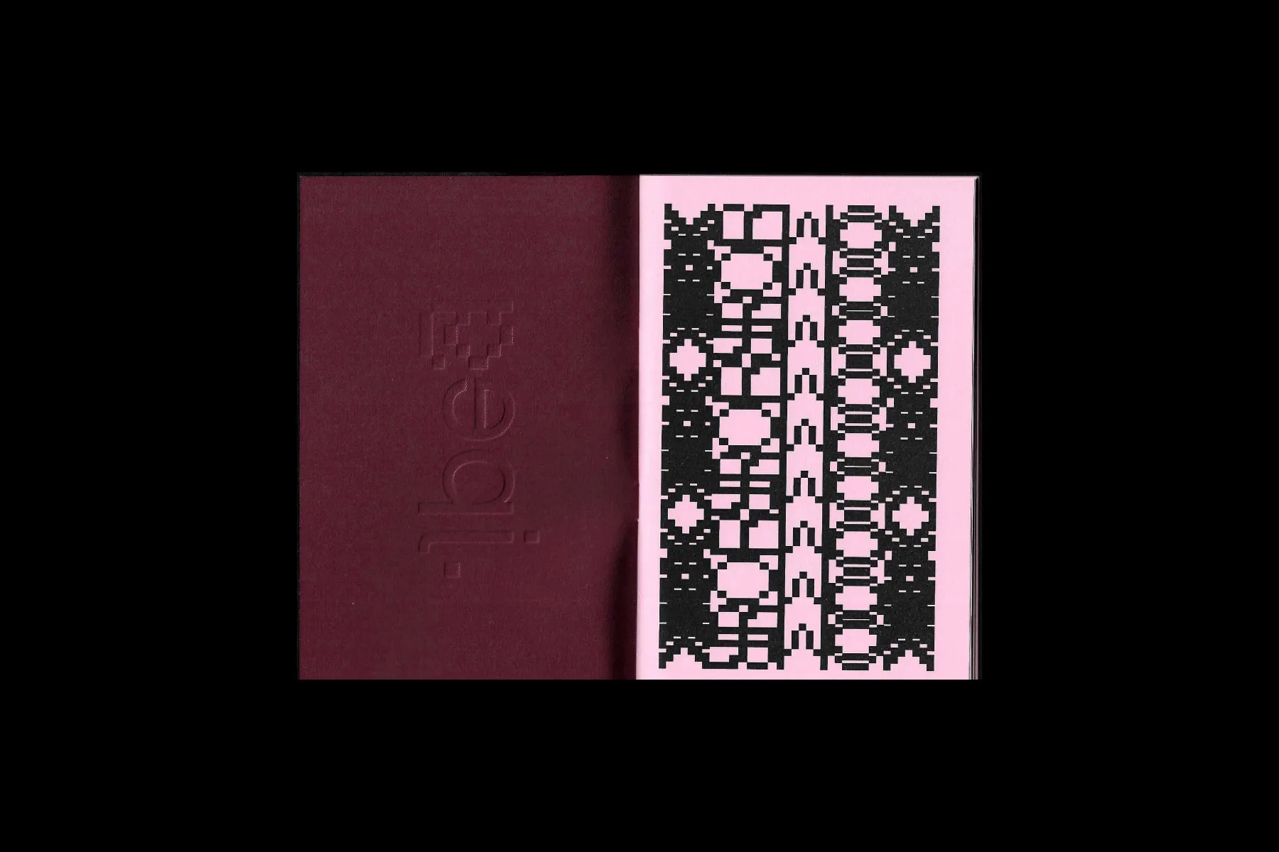 The zine's claret cover beside an open pink spread with a black brutalist pattern, on black