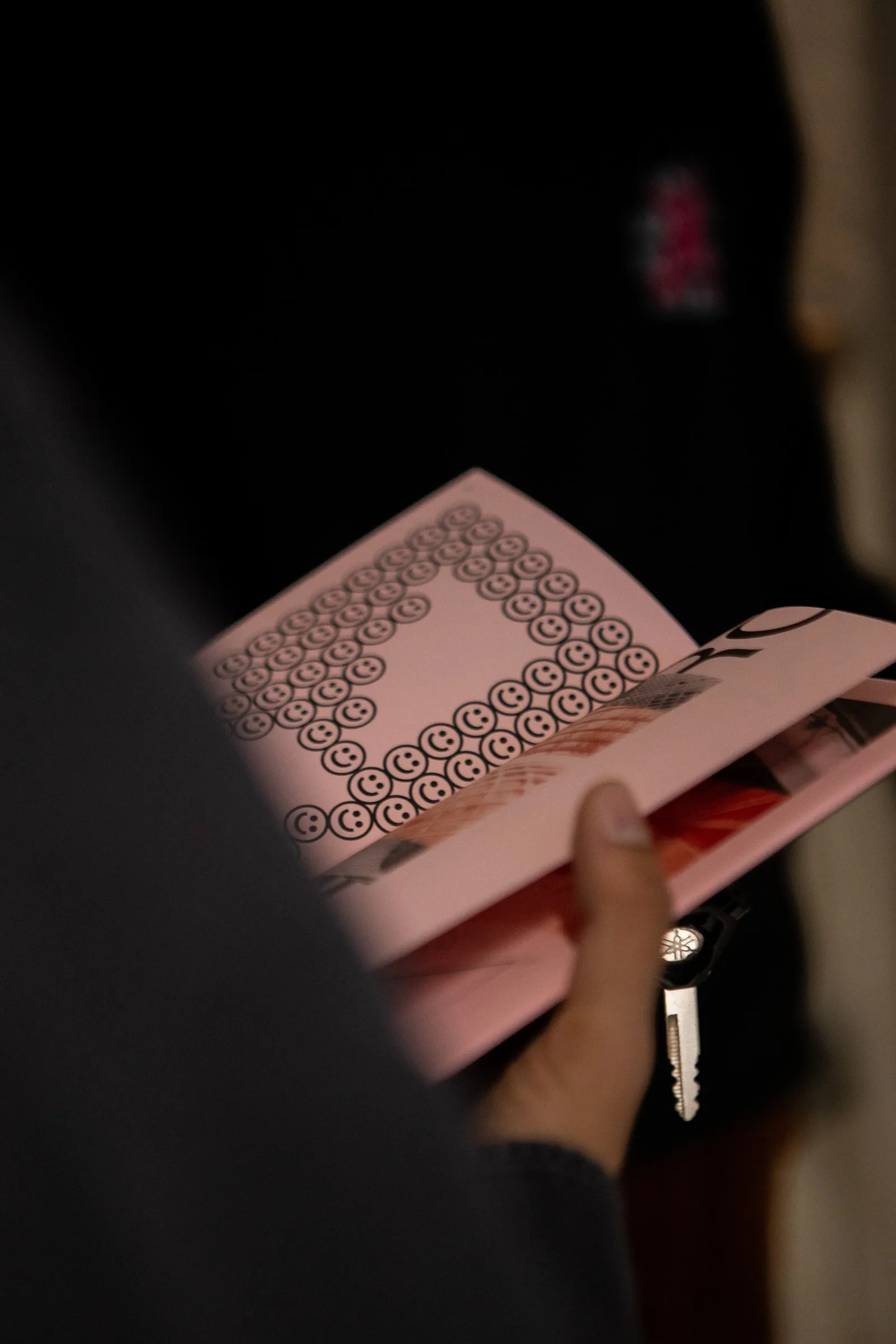 A hand holding the zine open at patterned pages in low light