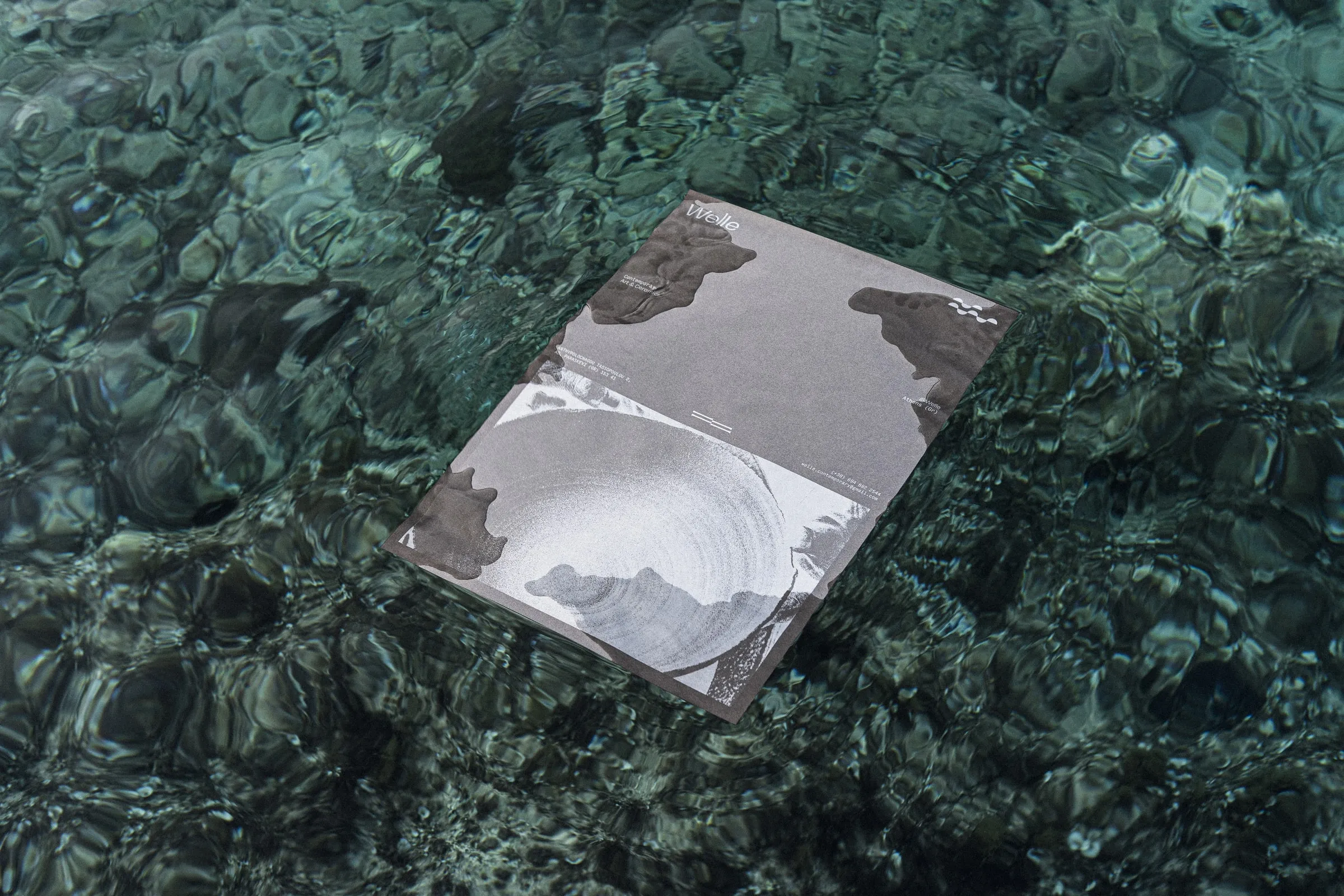 A Welle poster floating flat on rippling green water